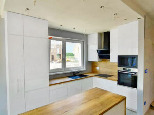 Biała kuchnia na wymiar Poznań po remoncie z wyspą i okapem. Fronty lakierowane.