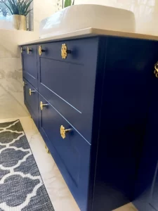 Granatowa szafka art deko na wymiar w Poznaniu, do łazienki ze złotymi uchwytami.