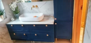 Granatowa szafka art deko na wymiar w Poznaniu, do łazienki ze złotymi uchwytami.