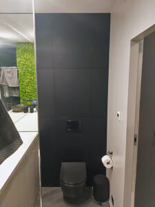 Czarno szara łazienka na zamówienie z zabudową geberitu oraz ścianą z żywego zielonegi mchu