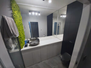 Czarno szara łazienka na zamówienie z zabudową geberitu oraz ścianą z żywego zielonegi mchu